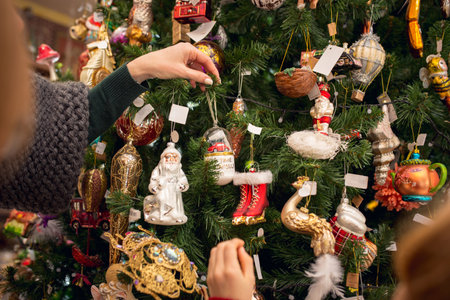 Christmas tree. Close up hands of mother and kids looking for home decoration and holiday's gifts in household store. Stylish retro things for greetings or design. Interior renovation, celebrating time.の写真素材