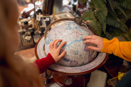 Huge globe. Close up childrens hands looking for home decoration and holidays gifts in household...