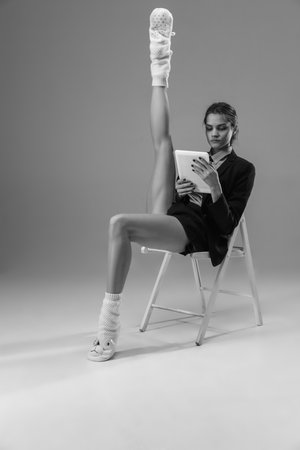 Report. Young fashionable, stylish woman wearing jacket and socks working from home. Fashion during insulation cause of coronavirus pandemic. Half business and half home style. Black and white.の写真素材