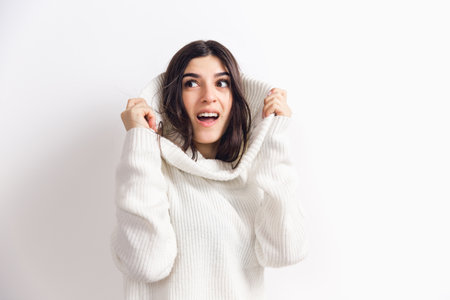 Cozy at home. Portrait of beautiful brunette woman in comfortable soft longsleeve isolated on white studio background. Home comfort, emotions, facial expression, winter mood concept. Copyspace.の写真素材