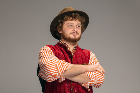 Hands crossed. Happy smiling man dressed in traditional Austrian or Bavarian costume gesturing isolated on grey studio background. Copyspace. The celebration, oktoberfest, festival, traditions concept.の写真素材