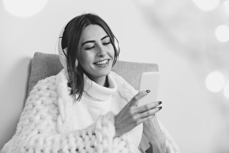 Scrolling. Portrait of beautiful brunette woman in comfortable soft longsleeve isolated on white studio background. Home comfort, emotions, facial expression, winter mood concept. Copyspace.の写真素材