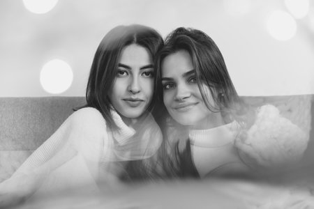 Warm. Portrait of beautiful brunette women in comfortable soft longsleeves on studio background, black and white. Home comfort, emotions, facial expression, winter mood concept. Friendship.の写真素材