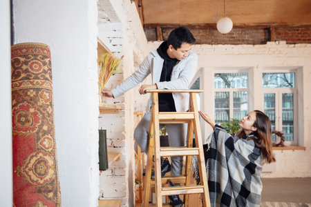 Preparing. New property owners, young couple moving to new home, apartment, look happy. Dream, love, relationship, real estate and interior concept. New life together. Caucasian woman and asian man.の写真素材
