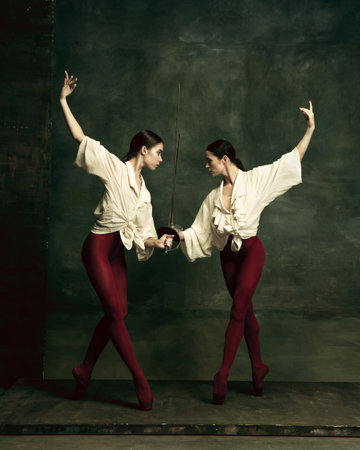 Emotions. Two young female ballet dancers like duelists with swords on dark green background....