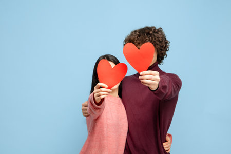 Showing hearts. Beautiful couple in love on blue studio background. Saint Valentines Day, love, relationship and human emotions concept. Copyspace. Young man and woman look happy together.の写真素材