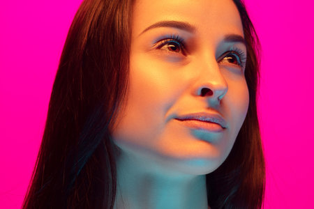 Close up caucasian womans portrait isolated on pink studio background in mixed neon light. Beautiful female model. Concept of human emotions, facial expression, sales, ad, fashion. Beauty.の写真素材