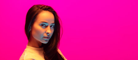 Serious. Caucasian womans portrait isolated on pink studio background in mixed neon light. Beautiful...