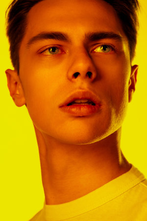 Lips. Handsome caucasian mans portrait isolated on orange studio background in neon, monochrome....