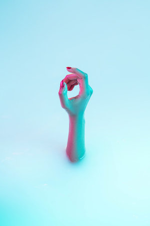Trying to call somebody. Close up female hand gesturing from the milk bath with soft white glowing in neon light. Copyspace for advertising. Sales, symbols, urban style concept. Modern neoned colors.の写真素材