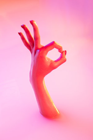 Nice, ok symbol. Close up female hand gesturing from the milk bath with soft white glowing in neon light. Copyspace for advertising. Sales, symbols, urban style concept. Modern neoned colors.の写真素材
