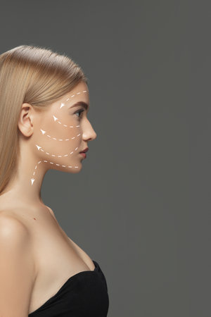 Beautiful female face with lifting up arrows isolated on grey background. Concept of bodycare,...