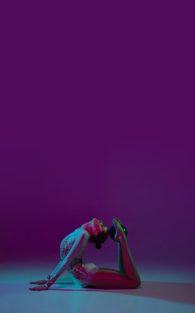Flyer. Young female athlete, rhythmic gymnastics artist dancing, training with tape isolated on purple studio background in neon light. Beautiful girl practicing with equipment. Grace in performance.の写真素材