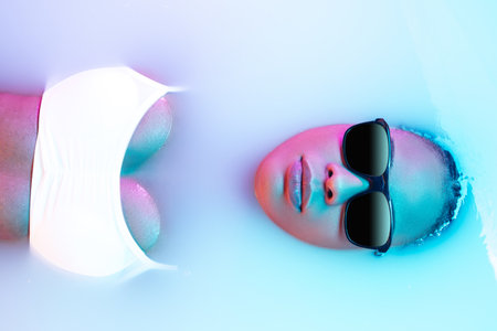 Tropic. Beautiful female face in the milk bath with soft glowing in blue-pink neon light. Copyspace...