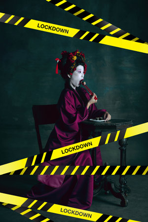 Young japanese woman as geisha isolated on dark green background. Eating sushi behind limiting tapes...