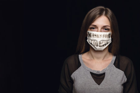 Woman wearing protective face mask with sign masks for 100 days in USA, America. Copyspace, black background.の写真素材