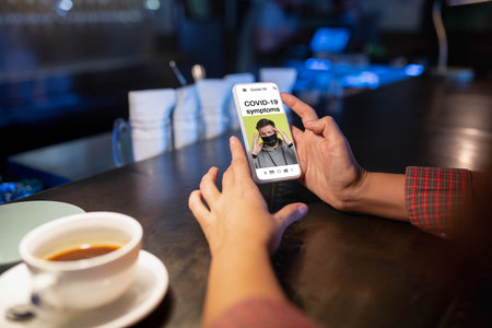 Be ready. Close up hands holding smartphone, cellphone with COVID symptoms on the screen. Staying safe during lockdown. Modern tech and healthcare. Online information and news. Lifestyle.の写真素材