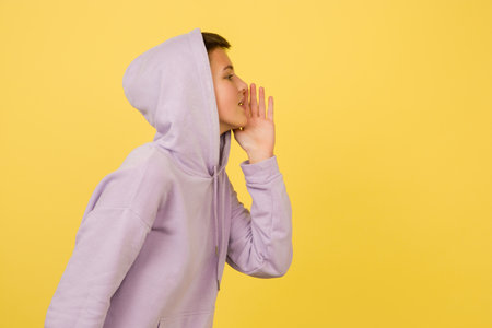 Whispering secretly. Caucasian girls portrait isolated on yellow background with copyspace....