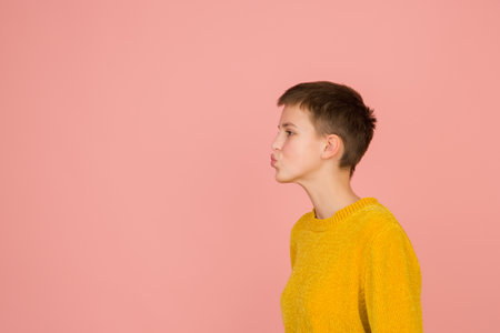 Sending kisses. Caucasian girls portrait on coral pink studio background with copyspace for ad. Beautiful female model in sweater. Concept of human emotions, facial expression, sales, ad, fashion.の写真素材
