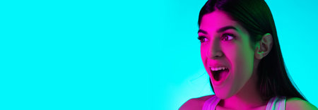 Shocked. Close up brunette womans portrait isolated on blue studio background in mixed neon light....