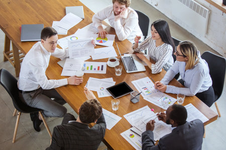 Top view. Diverse group of co-workers having casual discussion in office. Executives during friendly...