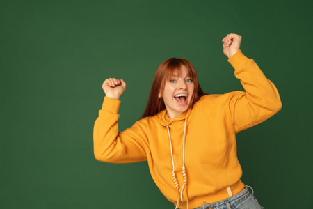 Winner. Caucasian womans portrait isolated on green studio background with copyspace. Beautiful...