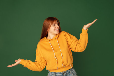 Showing. Caucasian womans portrait isolated on green studio background with copyspace. Beautiful...
