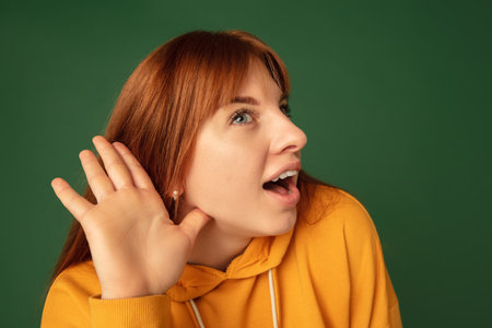 News listening. Caucasian womans portrait on green studio background with copyspace. Beautiful...