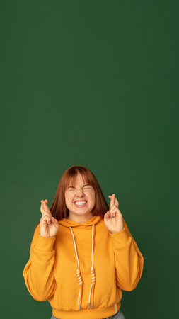 Fingers crossed. Caucasian womans portrait isolated on green studio background with copyspace....