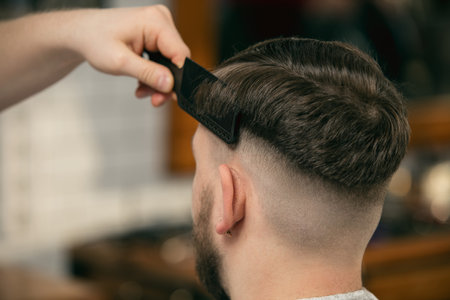 Fresh style. Close up of client of master barber, stylist during getting care and new look of hairstyle. Professional occupation, male beauty and self-care concept. Soft colors and focus, vintage.の写真素材