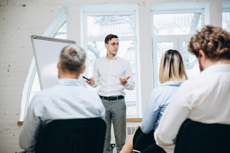 Results. Male speaker giving presentation in hall at university workshop. Audience or conference hall. Rear view of unrecognized participants in face masks. Scientific, business event, training.の写真素材