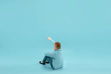 Pointing up. Childhood and dream about big and famous future. Pretty little boy isolated on blue...