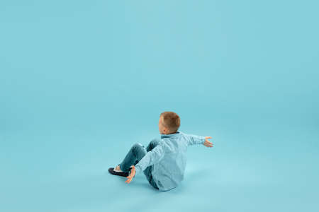 Astonished. Childhood and dream about big and famous future. Pretty little boy isolated on blue studio background. Childhood, dreams, imagination, education, facial expression, emotions concept.の写真素材