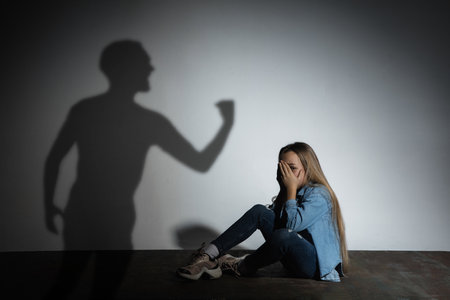 Domestic violence, abusing. Scared little caucasian girl, victim sitting close to white wall with...