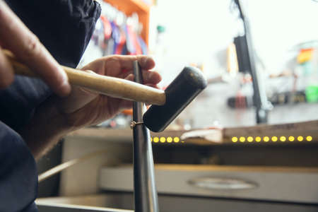 Rounding. Close up hands of jeweller, goldsmiths making of golden ring with gemstone using...