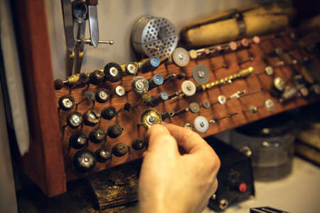 Accuracy. Close up hands of jeweller, goldsmiths making of silver ring with gemstone using...