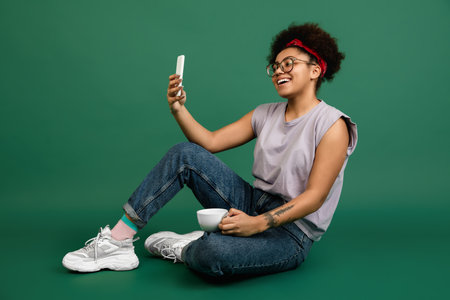Videochat. African-american beautiful womans portrait isolated on green studio background with...