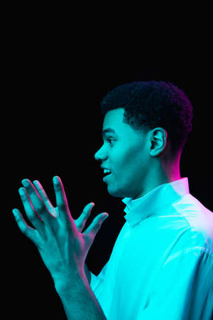 Astonished. African-american mans portrait on black studio background in multicolored neon light....