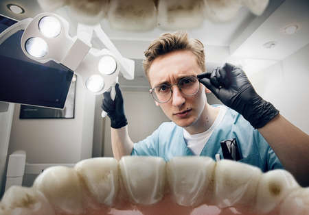 Preparing. Doctor looking into mouth, checking, examining teeth. Using professional tools and equipments. Healthcare and medicine, stomatology, feelings of patient. Look from inside the teeth.の写真素材