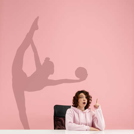 Young caucasian woman dreaming about future in big sport during her work in office. Shadow,...