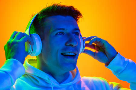 Delighted. Caucasian mans portrait isolated on yellow studio background in mixed neon light....