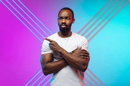 African-american young mans modern portrait on gradient pink-blue studio background in neon with...