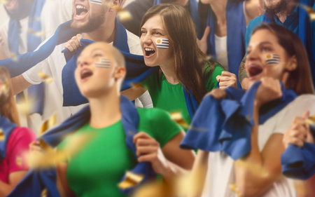 Uruguayan football, soccer fans cheering their team with a blue scarfs at stadium. Excited fans cheering a goal, supporting favourite players. Concept of sport, human emotions, entertainment.の写真素材