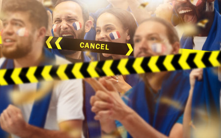 Lockdown. Francian soccer, football fans cheering for favourite sport team with bright emotions behind the limiting tapes with Cancel. Look excited, supporting, wondered. Blocked social life.の写真素材