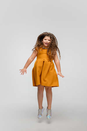 Jumping high. Happy, smiley little caucasian girl isolated on white studio background with copyspace for ad. Looks happy, cheerful. Childhood, education, human emotions, facial expression concept.の写真素材