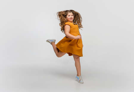 Jumping high. Happy, smiley little caucasian girl isolated on white studio background with copyspace...