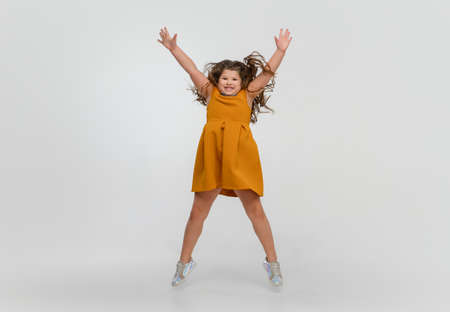Jumping high. Happy, smiley little caucasian girl isolated on white studio background with copyspace for ad. Looks happy, cheerful. Childhood, education, human emotions, facial expression concept.の写真素材