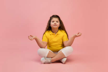 Happy, smiley little caucasian girl isolated on coral pink studio background with copyspace for ad. Looks happy, cheerful. Childhood, education, human emotions, facial expression concept.の写真素材