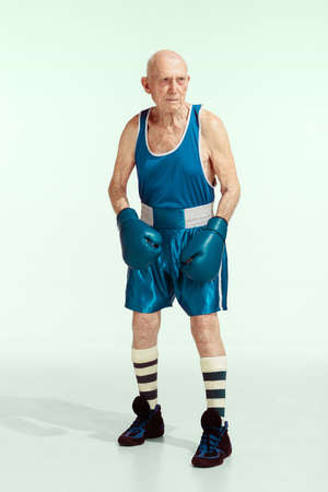 Senior man wearing sportwear boxing isolated on studio background. Caucasian male model in great shape stays active and sportive. Concept of sport, activity, movement, wellbeing. Copyspace, ad.の写真素材