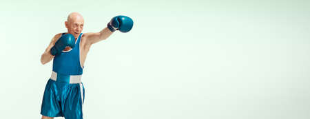 Flyer. Senior man wearing sportwear boxing on studio background. Caucasian male model in great shape...